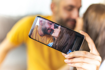 Close up of beautiful young couple is taking photo for their love story while using smartphone