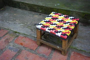 Simple short stool with colorful woven seat on the sidewalk in Southeast Asia