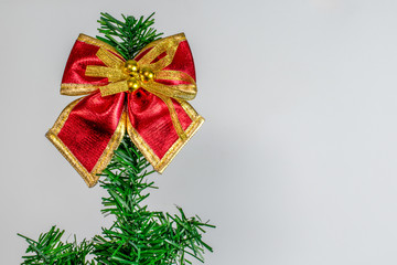 Close-up christmas ribbon at top of artificial pine tree