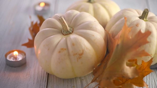 Thanksgiving holiday scene. Wooden table, decorated with pumpkins, autumn leaves and candles. 4K UHD video footage. 3840X2160