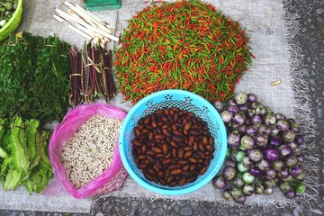 Colorful hot peppers, eggplant, beans, edible larva and pupa at an outdoor market in Luang Prabang, Laos