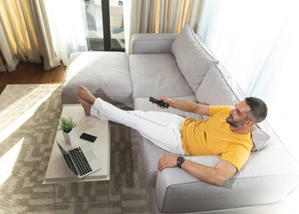 Top view of happy male sitting at home and having rest while watching TV
