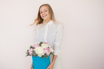 Woman with flowers in a hat box. Bouquet of peonies. Girl in business style, receives flowers or gives, Blue box.