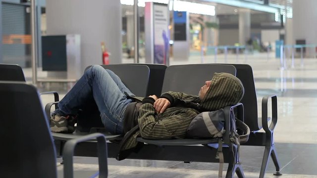 Young man sleeping while waiting the plane at airport passenger terminal
