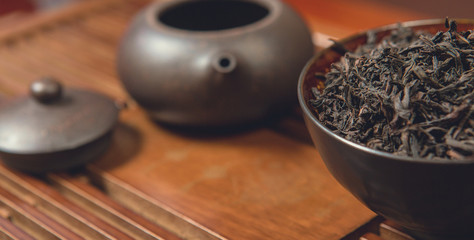 Chinese tea ceremony, Puer  in assortment, Ceramic brown teapot for brewing tea and a bowl with raw materials on a bamboo table