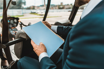 Close up of the elegant man sitting in the helicopter and holding necessary documents in his paper...
