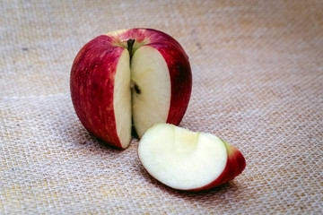 Red apple next to slices of another apple.