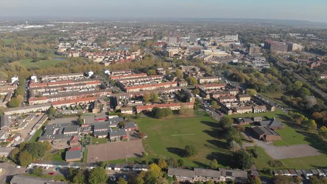 An aerial view of a residential area comprising of modern English houses on an autumn sunny day and the Basildon city center in the distance
