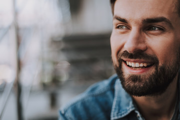 Naklejka premium Close up face of outgoing bearded man with attractive smile outdoor. Copy space
