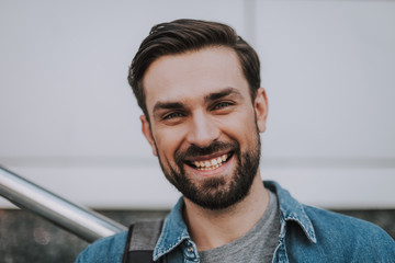 Naklejka premium Portrait of cheerful unshaven man with attractive smile expressing happiness. He locating at street