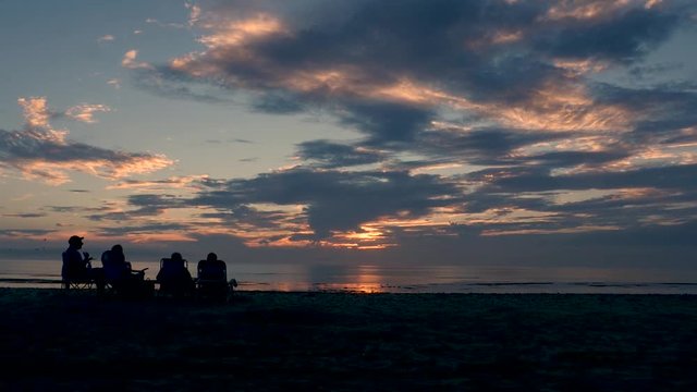 Timelapse of a cloud filled sunset on Cape Cod in New England with silhouetted people.