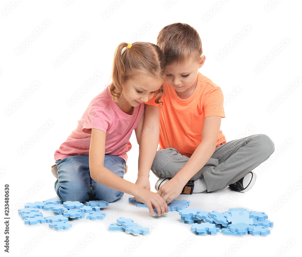 Wall mural Cute little children playing with puzzle on white background