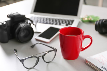 Blogger work space with cup of coffee and glasses on table indoors