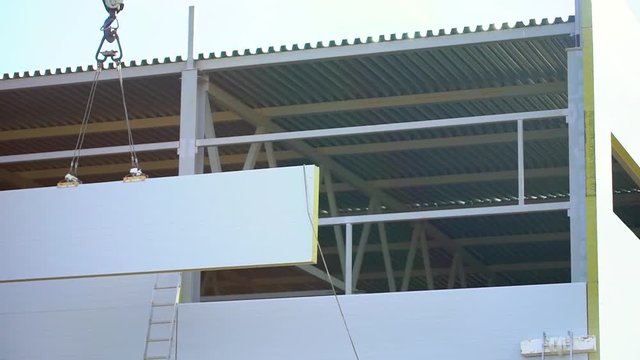 Workers, builders on the construction site. Installation sandwich panels, crane