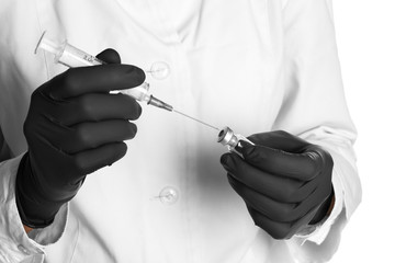 Doctor in medical gloves with syringe and vial, closeup