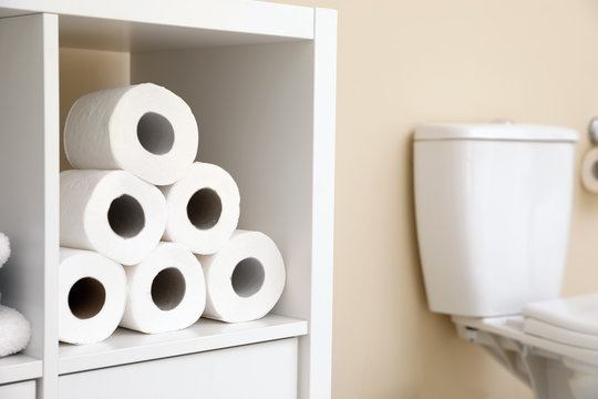 Toilet paper rolls on cabinet shelf in bathroom
