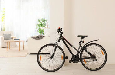 Bicycle near light wall in stylish room interior