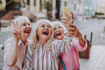 Happy white-haired women making selfie. Laughing females dressing stylish clothes