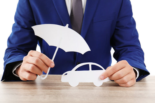 Insurance agent with paper cutout umbrella and car at table
