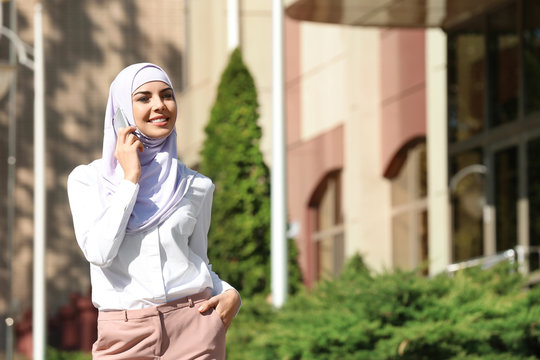 Muslim woman in hijab talking on phone outdoors