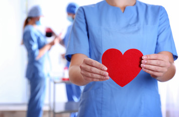 Doctor holding red heart at hospital, closeup. Donation day