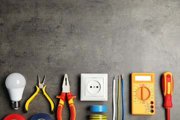Electrician's tools and space for text on gray background, flat lay