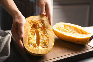 Woman holding cut spaghetti squash on table, closeup