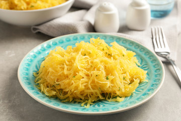Plate with cooked spaghetti squash on table