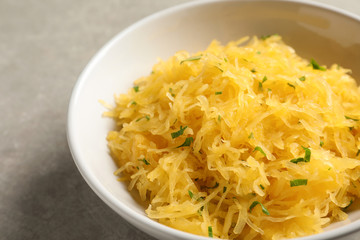 Bowl with cooked spaghetti squash on table, closeup