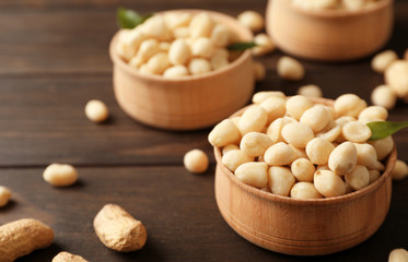 Shelled peanuts in wooden bowl on table