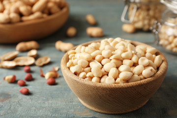 Shelled peanuts in wooden bowl on table