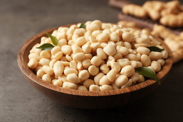 Shelled peanuts in wooden bowl on table