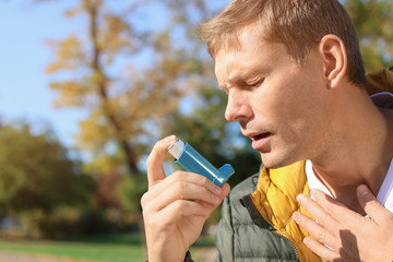 Man using asthma inhaler outdoors. Space for text - obrazy, fototapety, plakaty