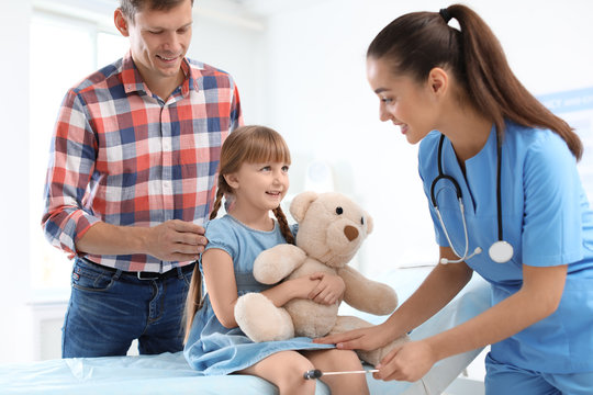 Children's doctor examining little girl near parent in hospital