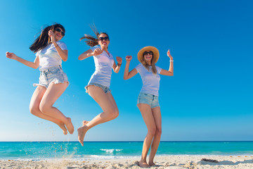 Tres mujeres muy sexys con camiseta blanca saltando y disfrutando un día de verano.