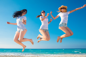 Tres mujeres muy sexys con camiseta blanca saltando y disfrutando un día de verano.