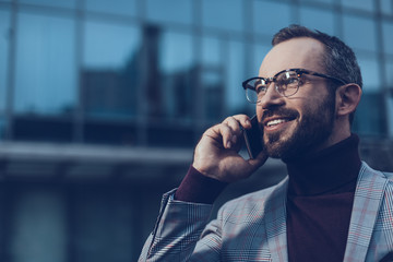 Emotional person. Positive bearded young man smiling and looking into the distance while having a...