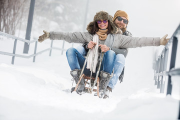 Young couple riding sled in snow