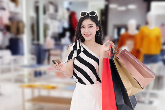 happy woman holding credit card and shopping bag at mall