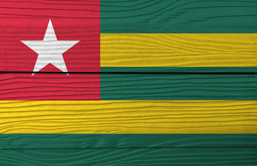Flag of Togo on wooden plate background. Grunge Togolese flag texture, Five equal horizontal bands of green alternating with yellow; with a red canton bearing a white star.