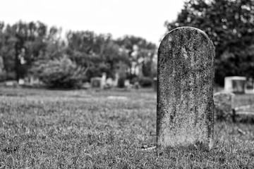 Black and white image of a tombstone in a cemetery.