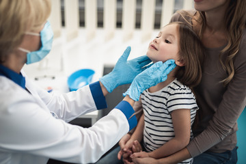 Concept of professional consultation in therapist system. Pediatrician woman examining tonsils of...