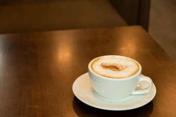 Close up a cup of hot cappuccino coffee place on wodden table