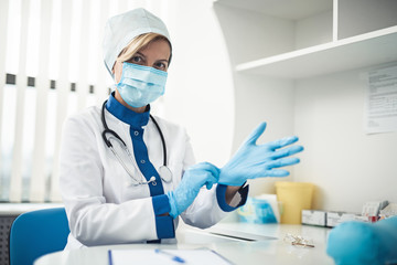 Professional laboratory investigations in healthcare system. Close up waist up portrait of lady doctor in medical uniform wearing gloves for making haemanalysis