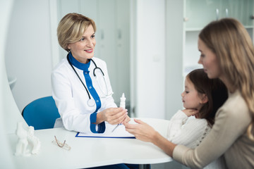 Concept of professional consultation in therapist practice. Waist up portrait of pediatrician woman giving nasal drops to young woman with daughter