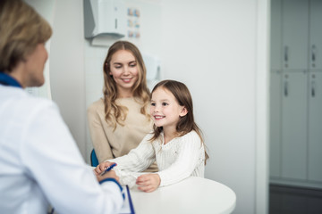 Concept of professional consultation in healthcare system. Waist up portrait of pediatrician woman consulting mother and her cheerful daughter in practice office