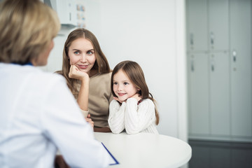 Concept of professional consultation in healthcare system. Waist up portrait of pediatrician woman consulting mother and her daughter in practice office