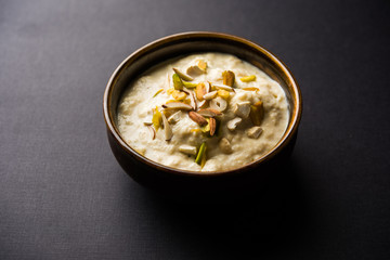 Fototapeta na wymiar Sweet Rabdi or Lachha Rabri or basundi, made with pure milk garnished with dry fruits. Served in a bowl over moody background. Selective focus