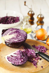 Shredded red cabbage on wooden cutting board.