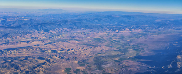 Aerial view of topographical Rocky Mountain landscapes on flight over Colorado and Utah during autumn. Grand sweeping views of rivers, mountain and landscape patterns. Top view, Rockies and Wasatch Fr